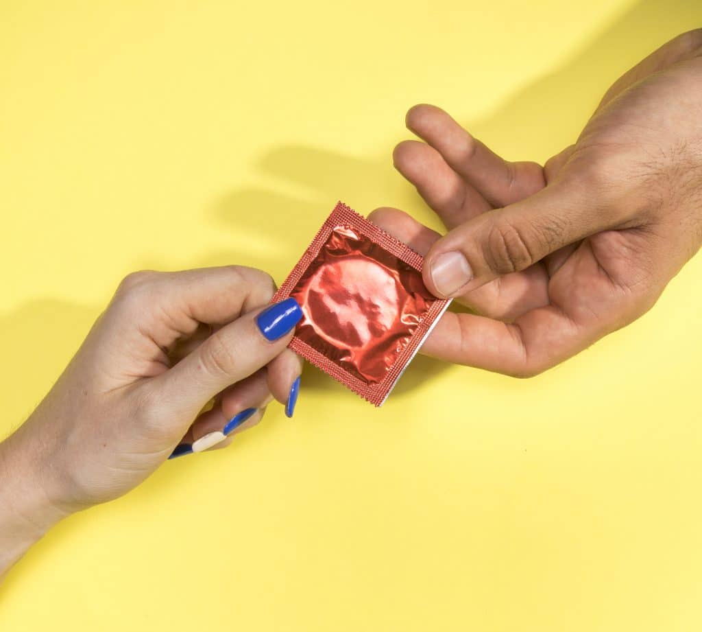 homem e mulher segurando um preservativo
