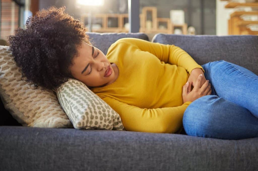 Uma mulher sofrendo com cólicas, um dos sintomas da endometriose.
