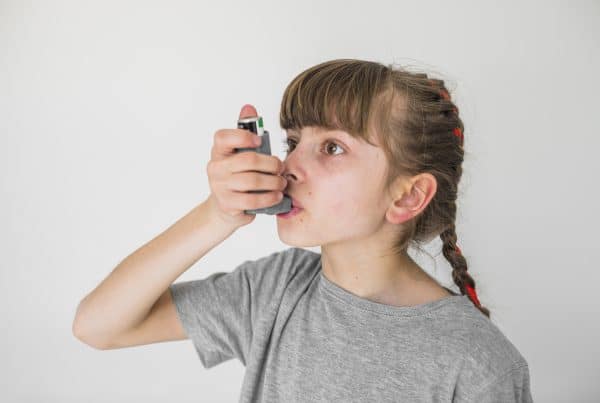 Criança com asma usando dispositivo em aerossol