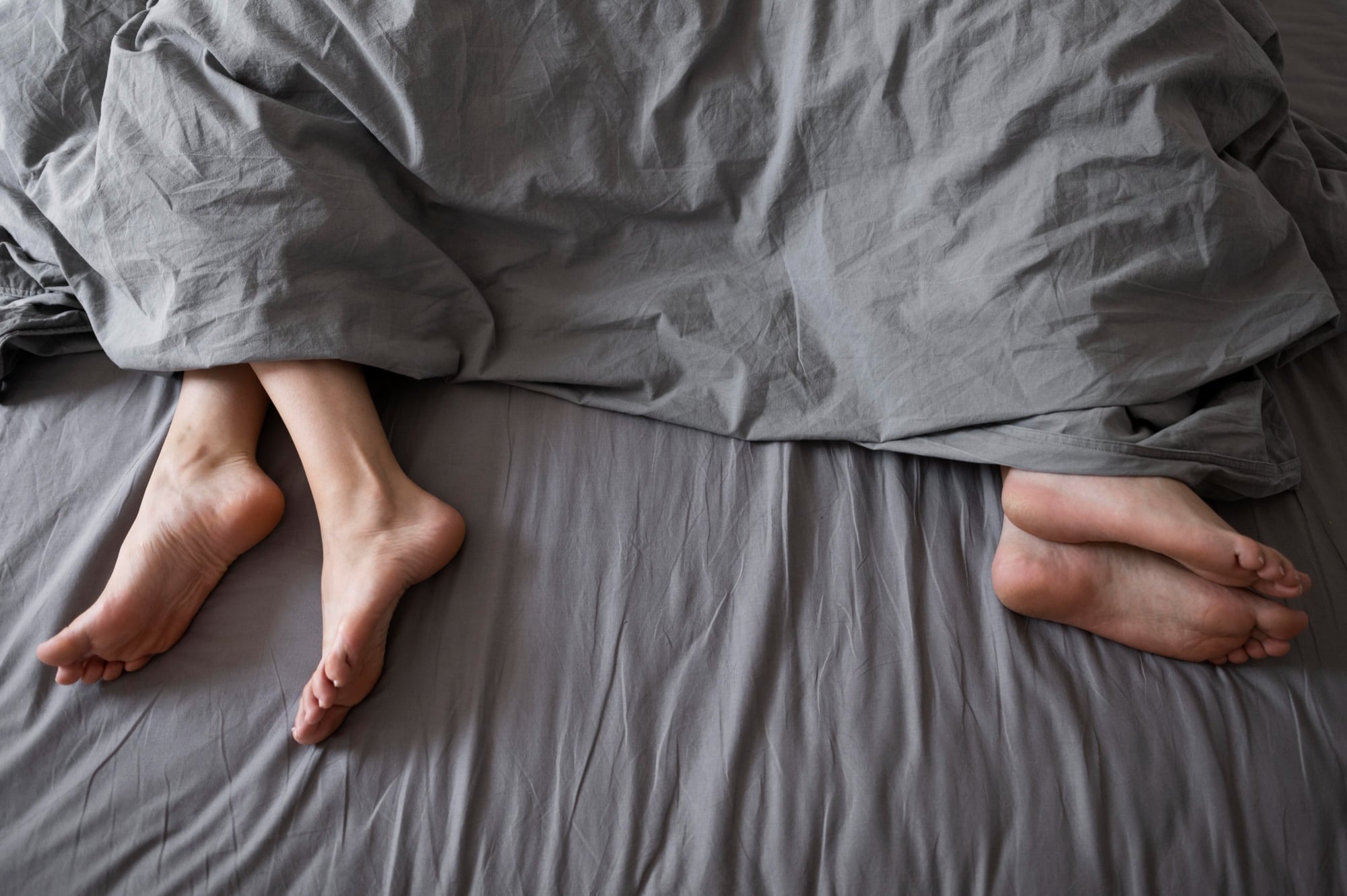 Cama de casal com duas pessoas dormindo afastadas