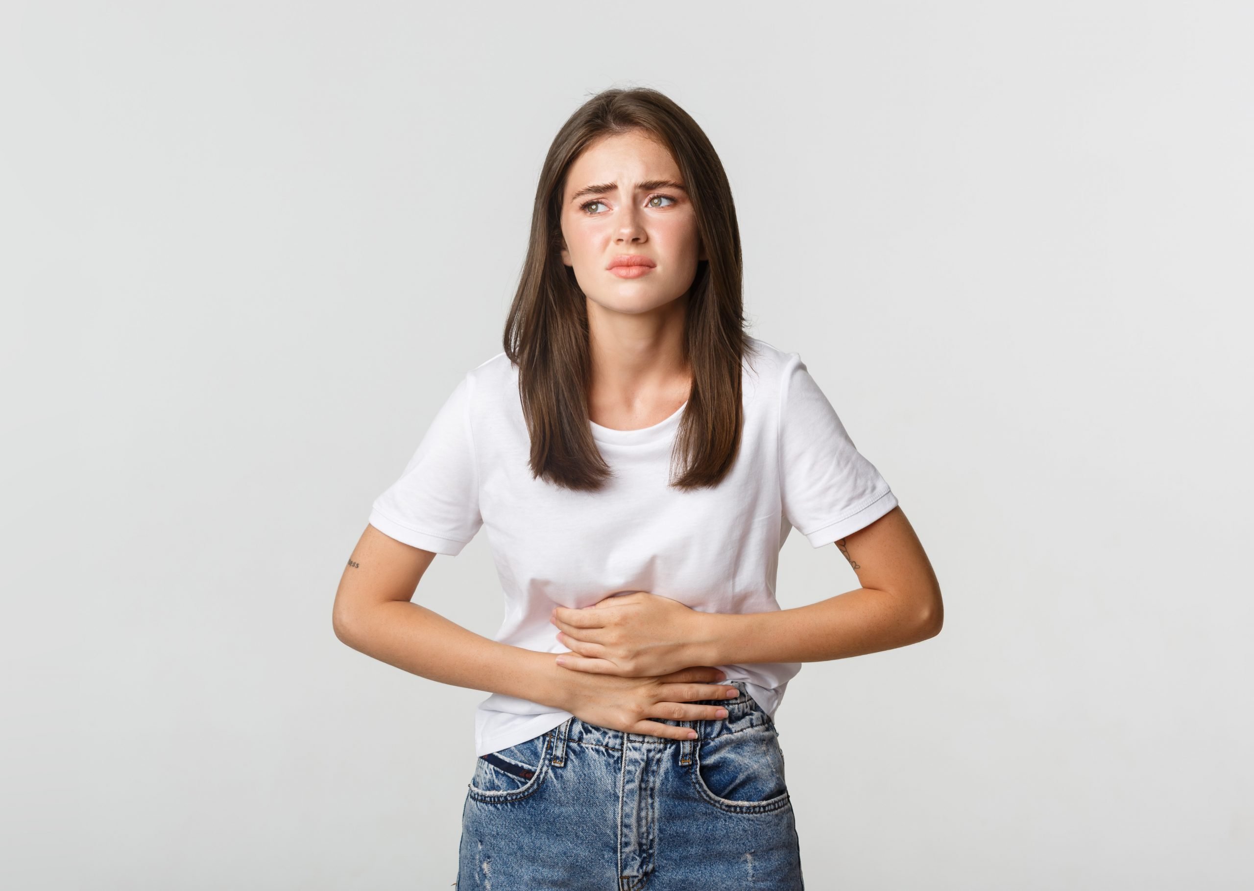 Mulher branca com expressão de desconforto, segurando a mão sobre a região abdominal, indicando síndrome nefrótica